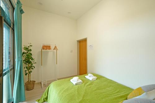 a bedroom with a green bed with towels on it at Oji Natural Cosy House in Tokyo
