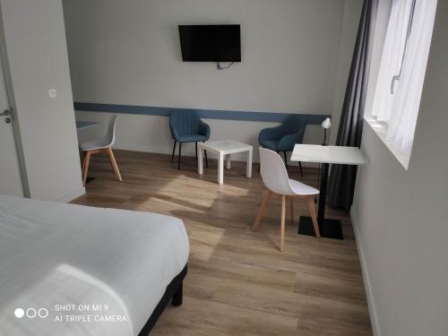 a hotel room with a bed and chairs and a tv at Atao Residence- Rennes Sud in Vern-sur-Seiche