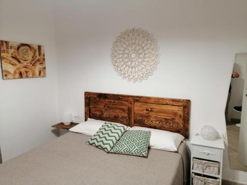 sypialnia z łóżkiem z drewnianym zagłówkiem i 2 poduszkami w obiekcie Tre Orologi w mieście Piombino