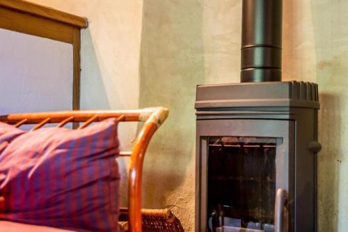 - un poêle à bois avec un oreiller à côté d'un lit dans l'établissement LE TIVOLI 1853, à Grandcamp-Maisy