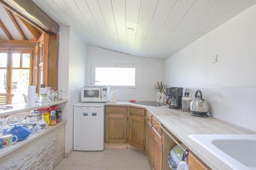 La cuisine est équipée d'un réfrigérateur blanc et d'un four micro-ondes. dans l'établissement LE TIVOLI 1853, à Grandcamp-Maisy