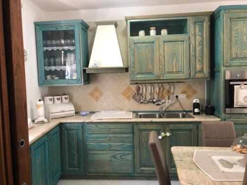 - une cuisine avec des placards verts et un évier dans l'établissement Casa Azzurra, à Santa Teresa Gallura