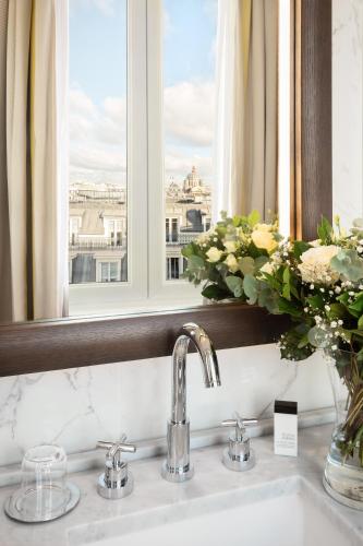 La salle de bains est pourvue d'un lavabo, d'une fenêtre et d'un vase de fleurs. dans l'établissement Hyatt Paris Madeleine, à Paris