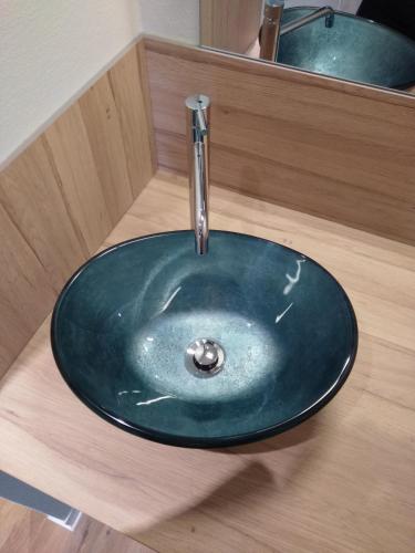 La salle de bains est pourvue d'un lavabo bleu et d'un robinet. dans l'établissement Malicorn' Appart-Hôtel, à Malicorne-sur-Sarthe