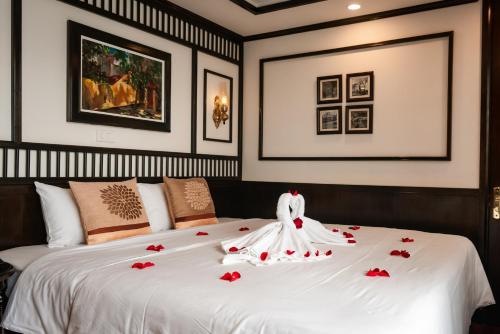 a white bed with red rose petals on it at Sena Cruises - Wonder On Lan Ha Bay in Ha Long