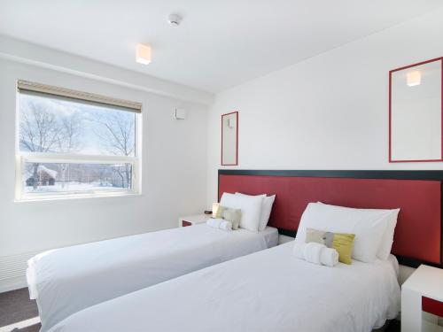 two white beds in a room with a window at Yamabiko Chalet in Niseko