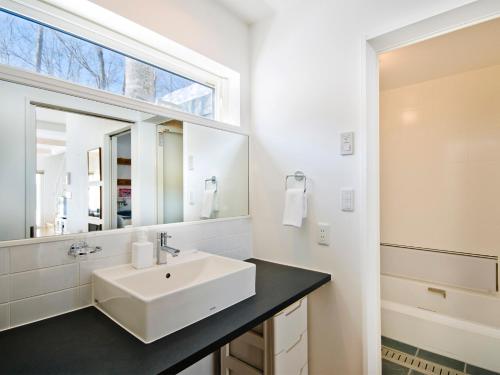 a white bathroom with a sink and a mirror at Yamabiko Chalet in Niseko