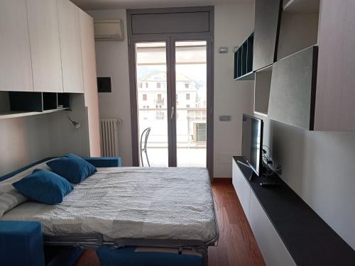 a bedroom with a bed with blue pillows and a television at Appartamenti Lungomare Savona in Savona