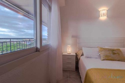 Schlafzimmer mit einem Bett und einem Fenster mit Aussicht in der Unterkunft Tres dormitorios vistas al mar junto a la playa in Punta Umbría