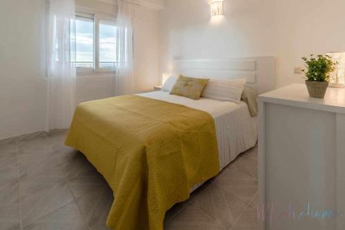 a bedroom with a bed with a yellow blanket on it at Tres dormitorios ,vistas al mar , junto a la playa in Punta Umbría