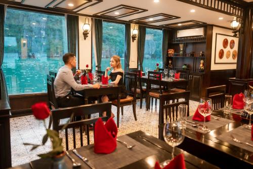 a man and woman sitting at a table in a restaurant at Sena Cruises - Wonder On Lan Ha Bay in Ha Long