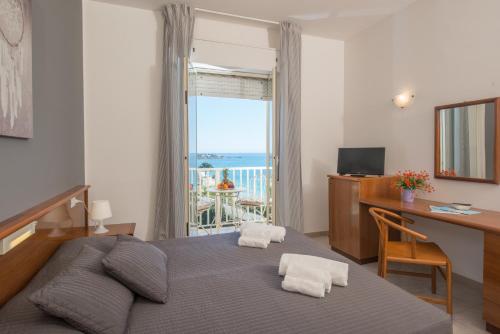 a bedroom with a bed with a desk and a window at Hotel President Sea Palace in Noto Marina