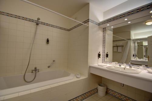 a bathroom with a tub and a sink and a mirror at Hôtel du Parc in Hardelot-Plage