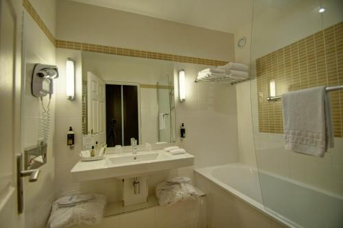 a white bathroom with a sink and a shower at Hôtel du Parc in Hardelot-Plage