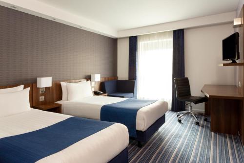 a hotel room with two beds and a desk at Holiday Inn Express Dunstable by IHG in Dunstable