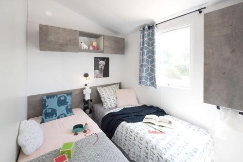 a small bedroom with two beds and a window at Camping Paradis le Rocher de la Granelle in Le Bugue