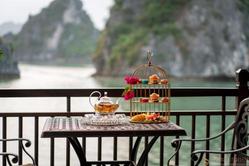 a table with a bird cage with food and a drink at Sena Cruises - Wonder On Lan Ha Bay in Ha Long