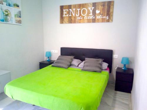 um quarto com uma cama verde e duas mesas de cabeceira em ENJOY Apart. Centro y Playa Cervantes em Málaga