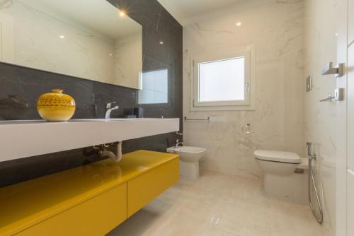 a bathroom with a yellow sink and a toilet at Residence Meridian Unità 2 in Villa San Pietro