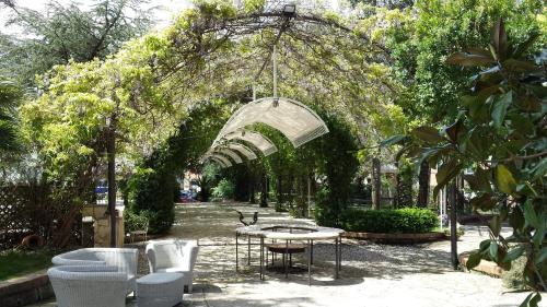 an archway with a table and chairs in a garden at Park Hotel San Michele in Martina Franca