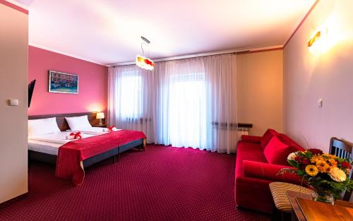 a hotel room with a bed and a red couch at Hotel Kasztelan in Dobczyce