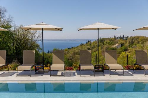 a group of chairs and umbrellas next to a swimming pool at Deville & Spa in Costermano sul Garda