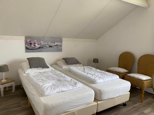 2 Betten in einem Zimmer mit 2 Stühlen in der Unterkunft Hello Zeeland - Vakantiehuis Schelde 254 in Breskens