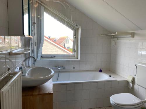 ein Badezimmer mit einer Badewanne, einem WC und einem Waschbecken in der Unterkunft Hello Zeeland - Vakantiehuis Schelde 254 in Breskens