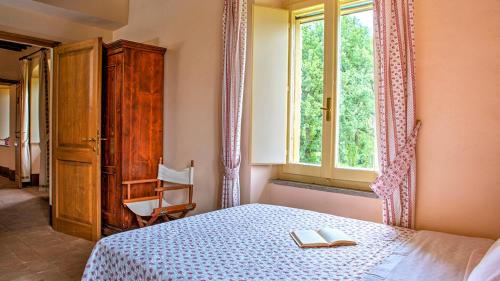 a bedroom with a bed with two books and a window at Casale Cicognola 12, Emma Villas in Massa Martana