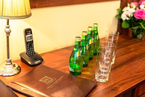 a group of green bottles on a table with a lamp and glasses at Hotel Kasztelan in Dobczyce