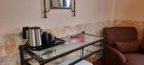 a glass table with a coffee maker and a chair at Olympic Fashion Hotels in Athens