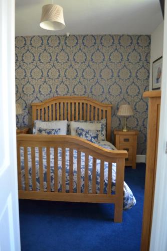 a bedroom with a wooden crib with a blue carpet at Coed-y-Fron in Betws-y-coed