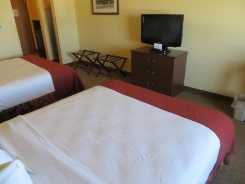a hotel room with two beds and a flat screen tv at Days Inn by Wyndham Ellis in Ellis