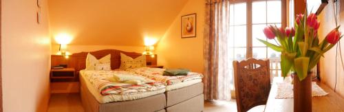 a bedroom with a bed and a vase of flowers at Pension Grünes Herz in Tonndorf