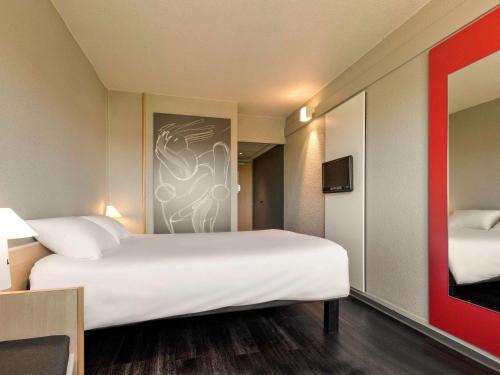 une chambre d'hôtel avec un grand lit et une télévision dans l'établissement ibis Saint Dizier, à Saint-Dizier