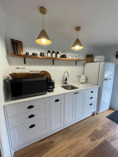 a white kitchen with a sink and a refrigerator at Amaroo Escape in Coneac