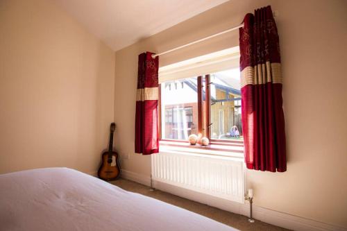 a bedroom with a bed and a window with red curtains at Derry City Private Apartment in Culmore