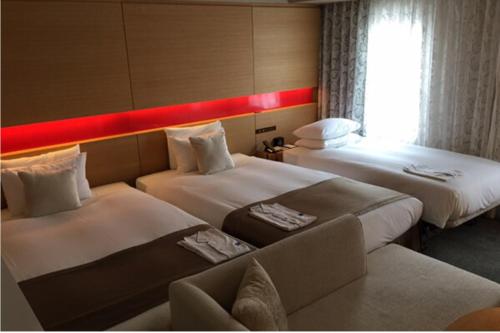 a hotel room with two beds and a couch at Hotel Metropolitan Akita in Akita