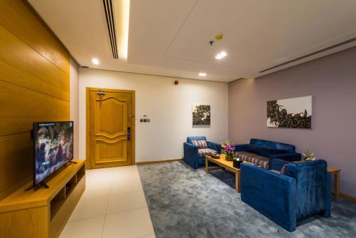 a living room with blue couches and a flat screen tv at Boudl Al Munsiyah in Riyadh