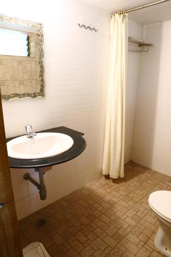 a bathroom with a sink and a shower curtain at Pinewood Resort in Karjat