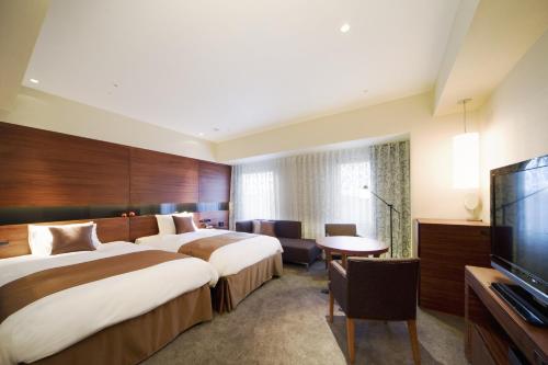 a hotel room with two beds and a flat screen tv at Hotel Metropolitan Akita in Akita