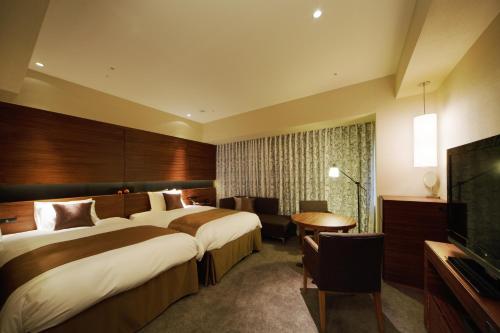 a hotel room with two beds and a flat screen tv at Hotel Metropolitan Akita in Akita