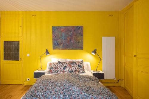 Le Studio Gab's - Coup de coeur déco tout confort في كالوير - إيه - كوير: غرفة نوم صفراء بسرير ومصباحين