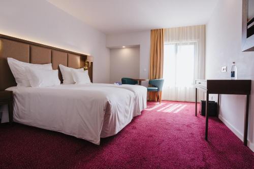 a hotel room with a large white bed and a piano at Hotel Premium Chaves - Aquae Flaviae in Chaves