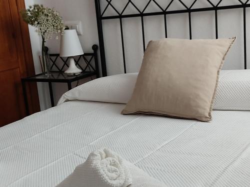 Una cama blanca con una almohada y una toalla. en Apartamentos Bolonia - M a n u e l a, en Bolonia