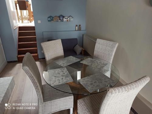 une table à manger en verre avec quatre chaises dans l'établissement L'Anse Rouge, vue sur le port, à Saint-Valery-sur-Somme