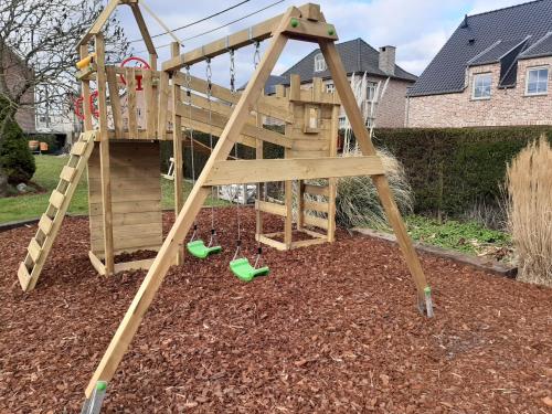 een houten speelset met een ladder en schommels bij 't Hof van Cremers in Geraardsbergen