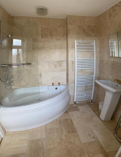 y baño con bañera, aseo y lavamanos. en Large 4 bedroom home in Boston Spa village In-between York, Harrogate and Leeds, Sleeps 9, en Boston Spa