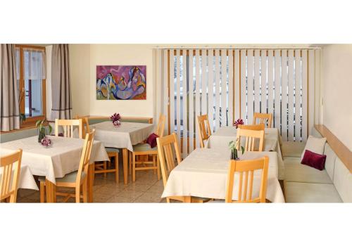 a dining room with white tables and chairs and a painting at Biotel Bertel Naturappartements in Brand