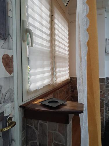 - une fenêtre avec des stores dans une chambre avec une table en bois dans l'établissement Casa Bella mbriana, à Naples